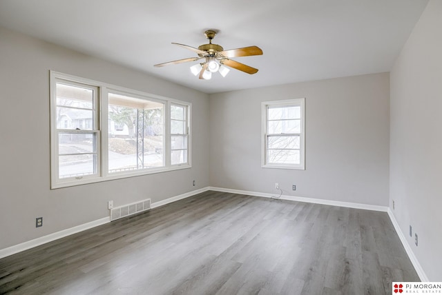 spare room with wood finished floors, baseboards, and visible vents