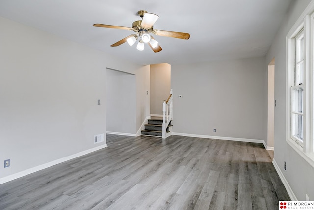 unfurnished room featuring stairway, baseboards, and wood finished floors