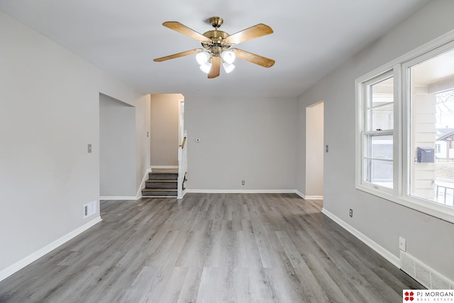 empty room featuring visible vents, stairs, baseboards, and wood finished floors