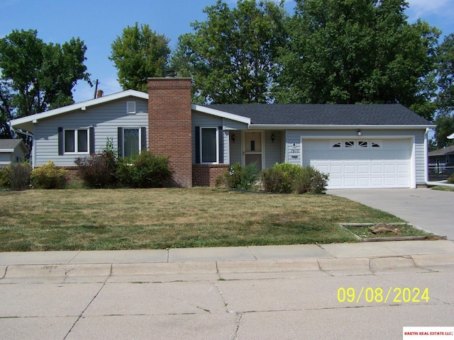 view of front facade featuring concrete driveway, a front yard, a garage, brick siding, and a chimney