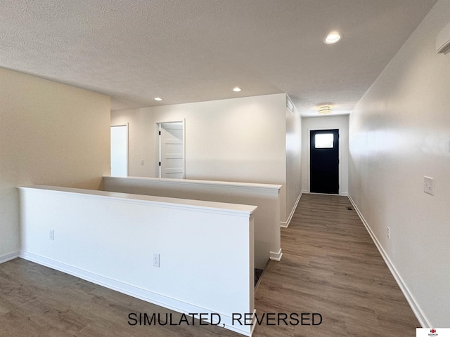 hall with recessed lighting, wood finished floors, baseboards, and a textured ceiling