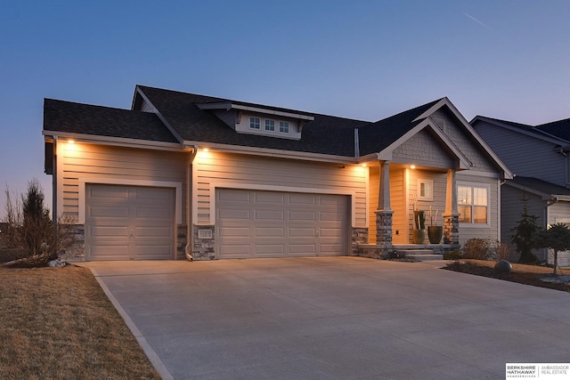 craftsman house featuring stone siding, driveway, and a garage