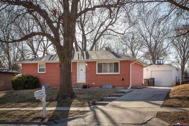 ranch-style house featuring brick siding, a shingled roof, a detached garage, concrete driveway, and an outbuilding