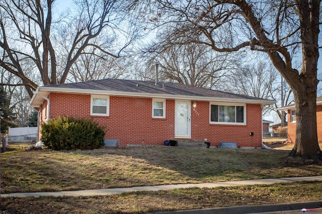 view of front of property with entry steps, brick siding, a front lawn, and fence