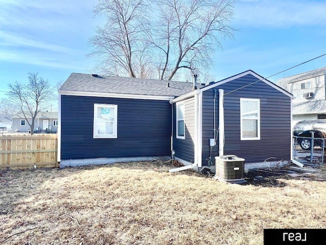 rear view of property featuring central air condition unit and fence