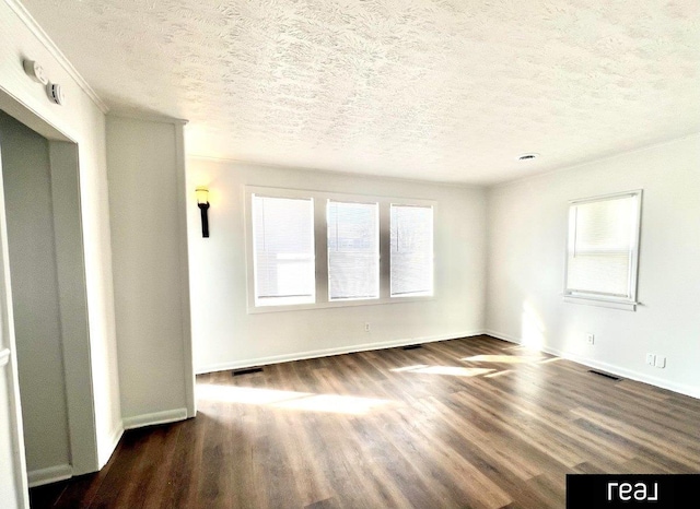 empty room featuring dark wood finished floors, visible vents, a textured ceiling, and baseboards