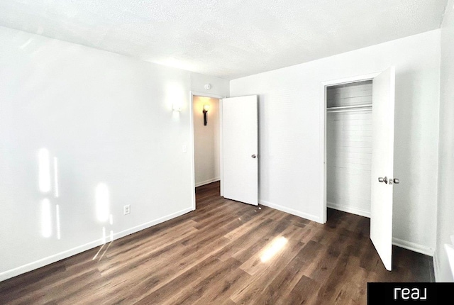 unfurnished bedroom featuring baseboards, wood finished floors, a closet, and a textured ceiling