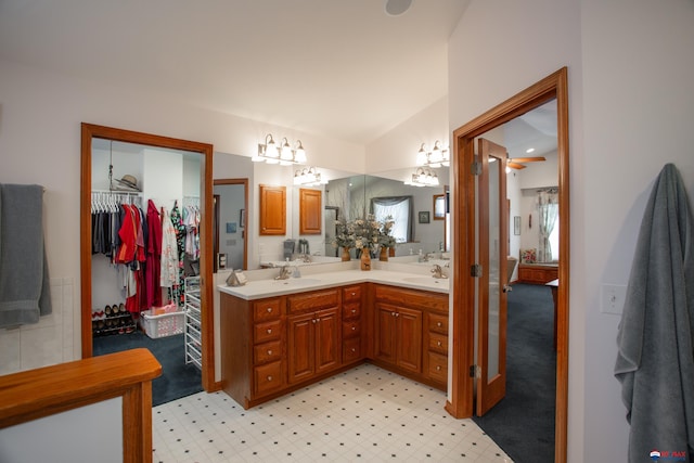 full bathroom featuring a walk in closet, lofted ceiling, double vanity, and a sink