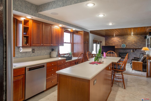 kitchen featuring light countertops, a kitchen breakfast bar, stainless steel dishwasher, a brick fireplace, and open floor plan