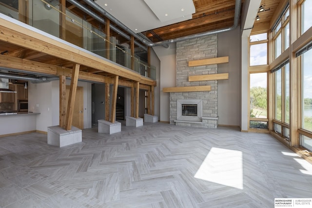 unfurnished living room featuring a stone fireplace, baseboards, and a towering ceiling