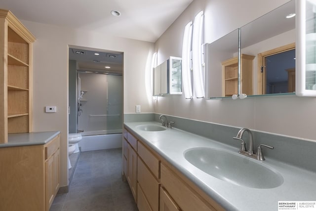 full bath featuring double vanity, toilet, shower / bath combination with glass door, and a sink