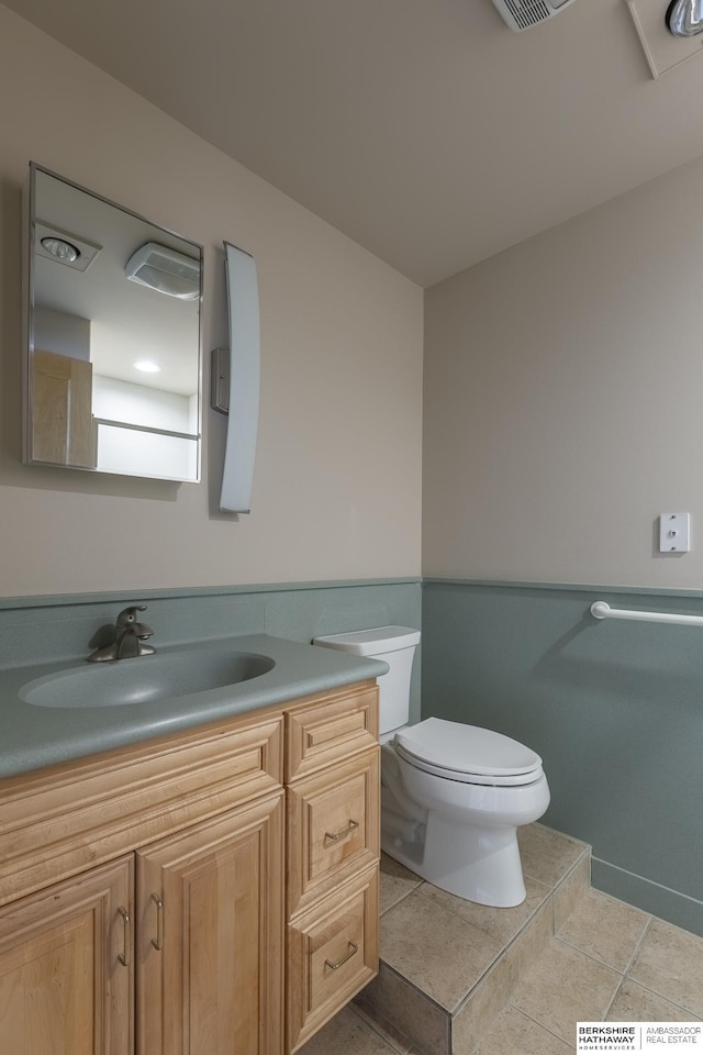 bathroom with vanity, toilet, tile patterned flooring, and wainscoting