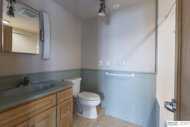 bathroom with toilet, vanity, and tile patterned flooring