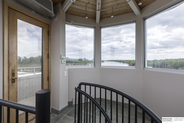 interior space with tile patterned floors, wood ceiling, a water view, and baseboards