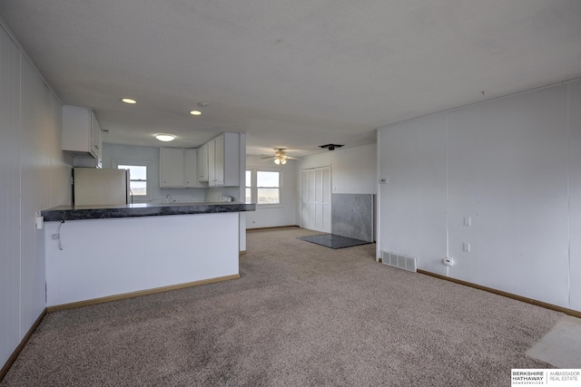 kitchen featuring dark countertops, visible vents, open floor plan, light carpet, and freestanding refrigerator