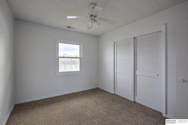 unfurnished bedroom featuring a ceiling fan, visible vents, a closet, a textured ceiling, and carpet flooring