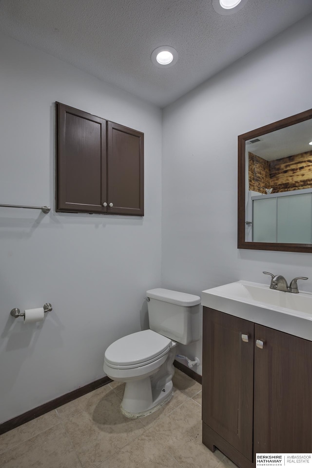 bathroom with baseboards, toilet, vanity, and a textured ceiling