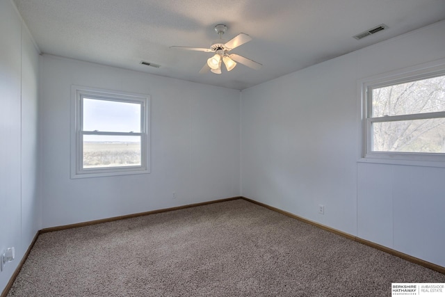 spare room featuring visible vents, carpet, and ceiling fan