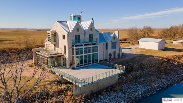 back of property featuring stucco siding, a water view, and a balcony