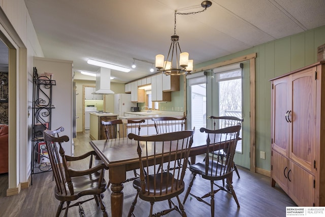 dining room featuring a notable chandelier, baseboards, and wood finished floors