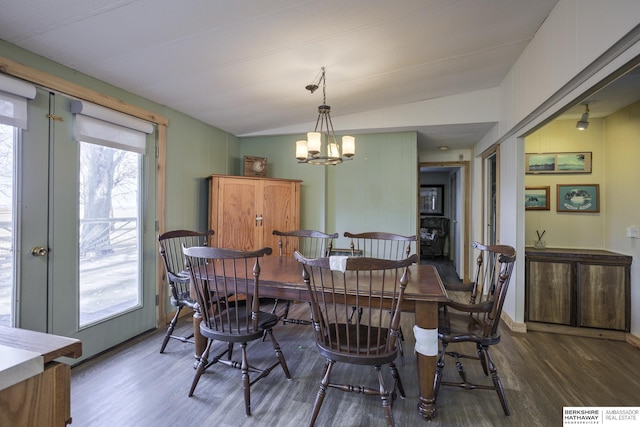 dining space with an inviting chandelier, vaulted ceiling, and wood finished floors