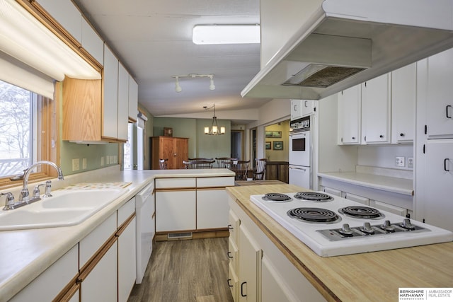 kitchen featuring white appliances, light countertops, extractor fan, and a sink