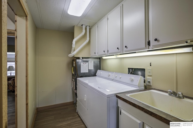 washroom featuring dark wood finished floors, cabinet space, independent washer and dryer, and a sink