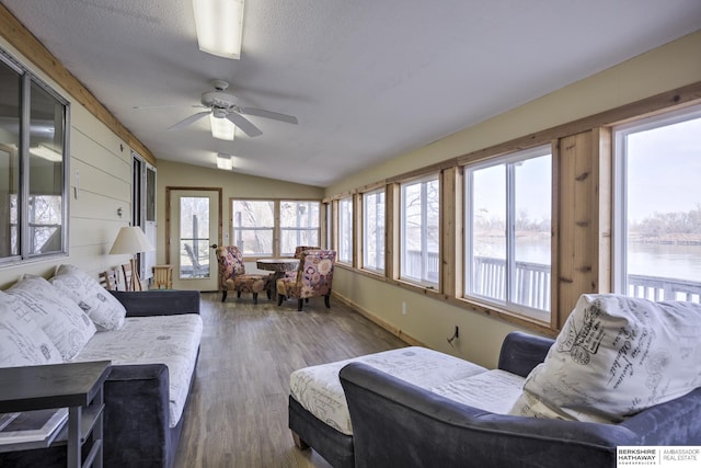 sunroom with a ceiling fan, lofted ceiling, a healthy amount of sunlight, and a water view