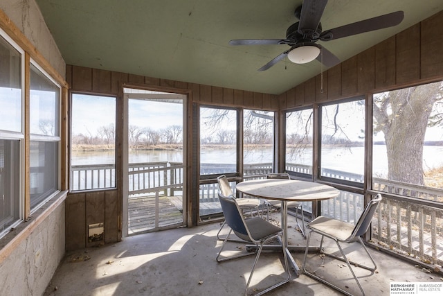 sunroom / solarium with a healthy amount of sunlight, a ceiling fan, lofted ceiling, and a water view