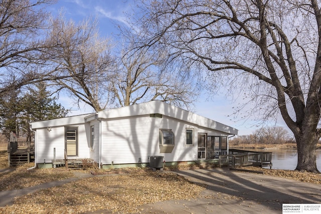 view of front facade featuring central air condition unit, a deck with water view, and a sunroom