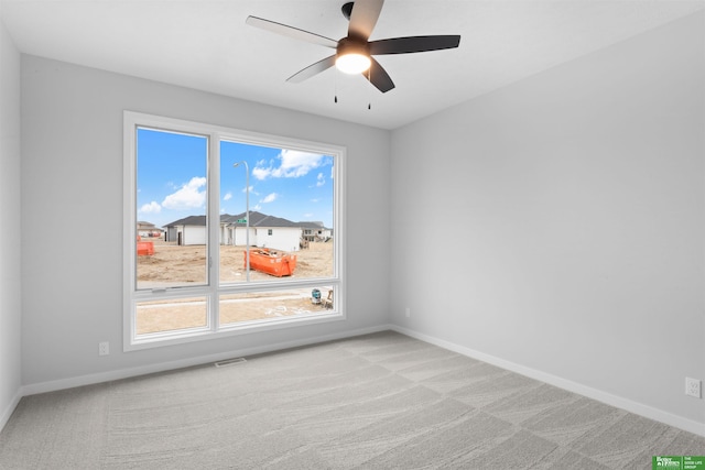 spare room featuring ceiling fan, baseboards, visible vents, and light carpet