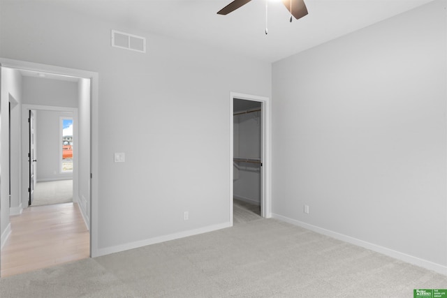 unfurnished bedroom featuring a spacious closet, visible vents, and light carpet