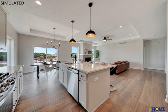 kitchen with visible vents, open floor plan, appliances with stainless steel finishes, light wood finished floors, and a raised ceiling