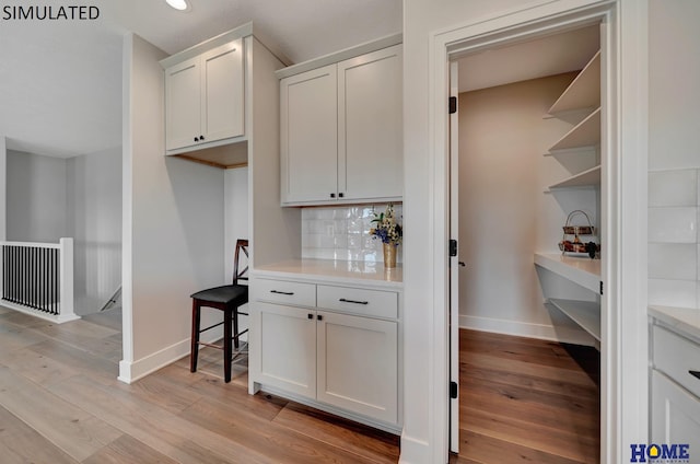 bar with light wood-type flooring, baseboards, and decorative backsplash