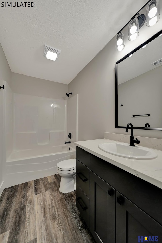 full bath with visible vents, tub / shower combination, vanity, wood finished floors, and a textured ceiling