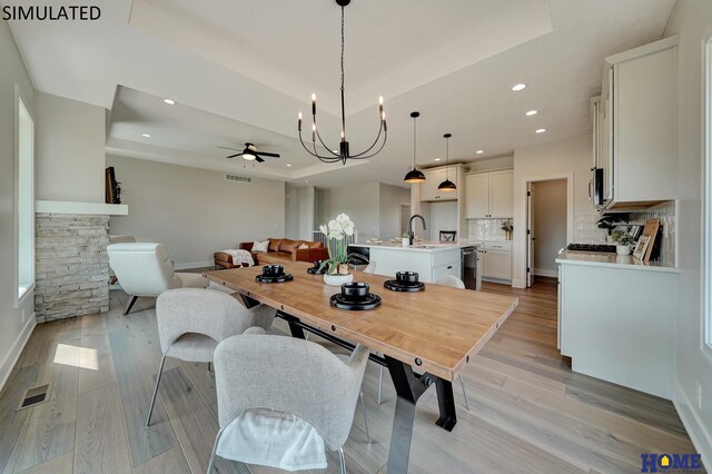 dining room featuring a raised ceiling, visible vents, and light wood-type flooring