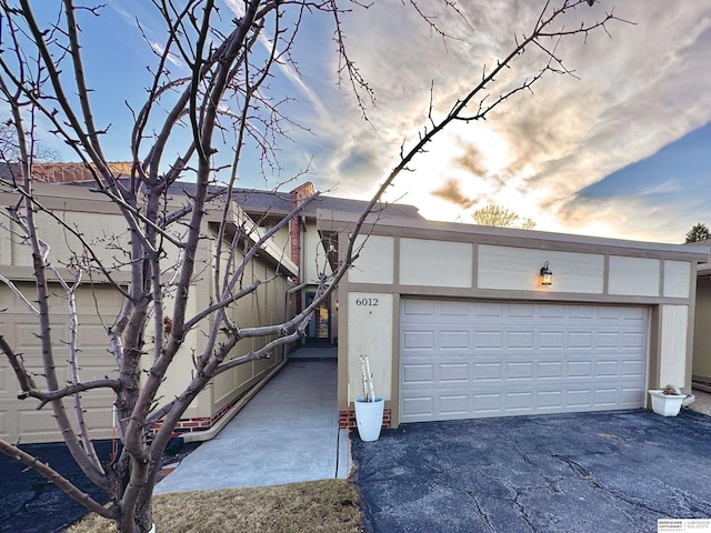 view of front of property featuring stucco siding, driveway, and a garage