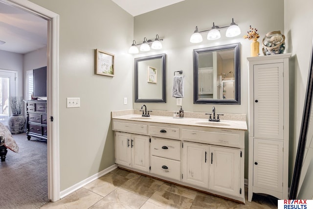 full bathroom featuring double vanity, baseboards, and a sink