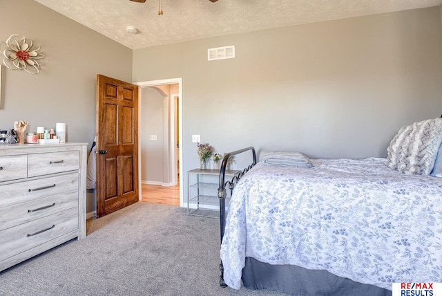 carpeted bedroom with baseboards, visible vents, a textured ceiling, and a ceiling fan