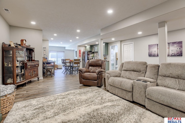 living area with visible vents, recessed lighting, and wood finished floors