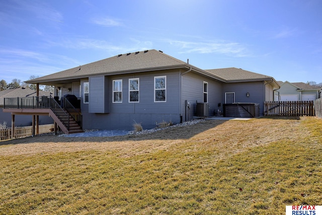 back of property with a shingled roof, stairway, central AC unit, a fenced backyard, and a yard