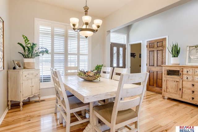 dining space with plenty of natural light, baseboards, light wood finished floors, and a chandelier