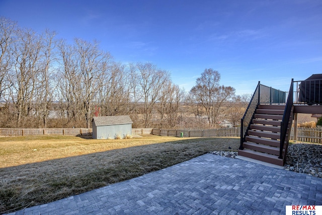 view of yard featuring a storage unit, a patio, a fenced backyard, an outdoor structure, and stairs