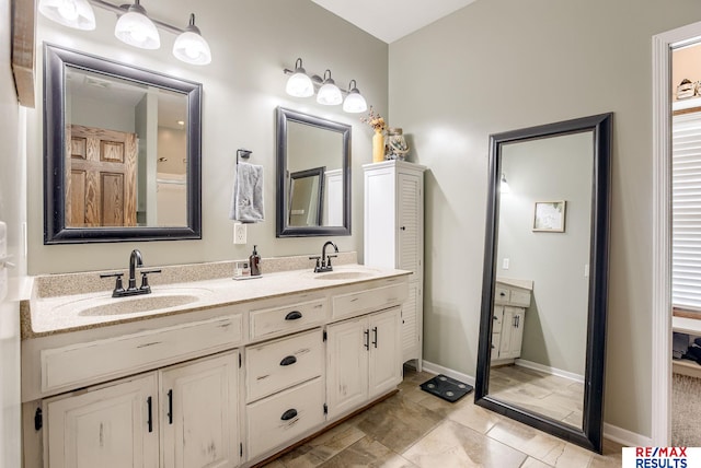 bathroom featuring double vanity, baseboards, and a sink