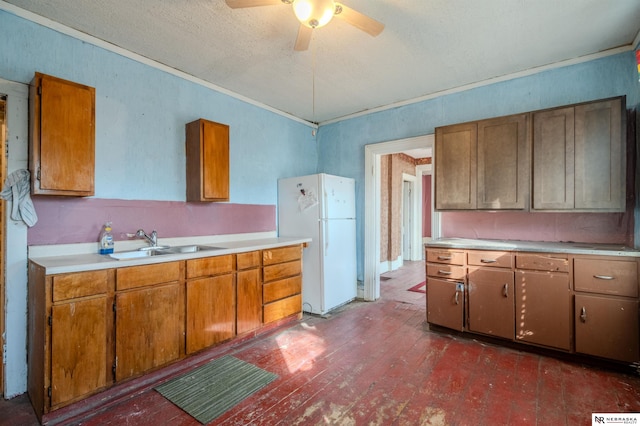 kitchen featuring a sink, brown cabinetry, light countertops, and freestanding refrigerator