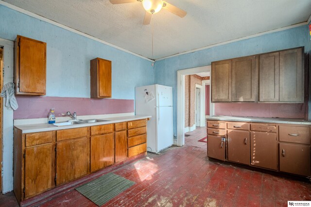 kitchen featuring a sink, brown cabinetry, light countertops, and freestanding refrigerator