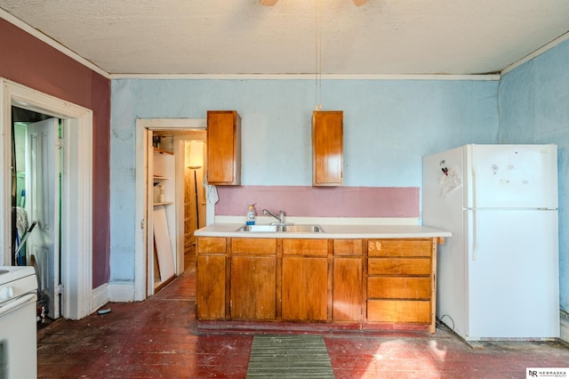 kitchen featuring light countertops, brown cabinets, white appliances, a textured ceiling, and a sink