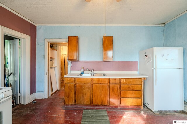 kitchen featuring light countertops, brown cabinets, white appliances, a textured ceiling, and a sink