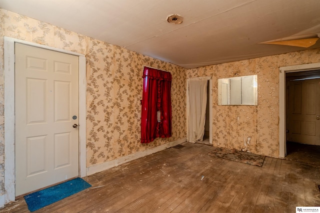 unfurnished room featuring baseboards, hardwood / wood-style flooring, and wallpapered walls