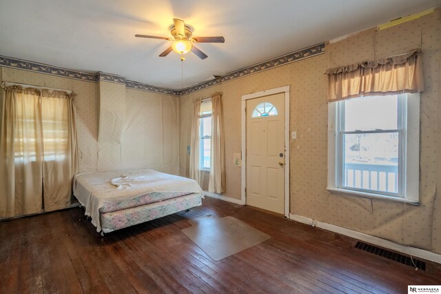 bedroom featuring hardwood / wood-style floors, a ceiling fan, baseboards, visible vents, and wallpapered walls